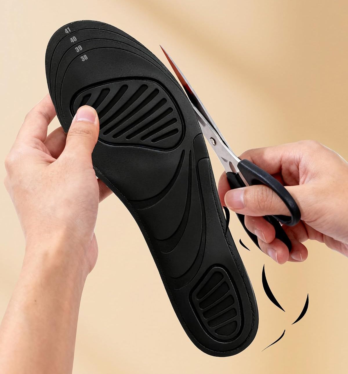 Hands trimming a black heated insole to size with scissors